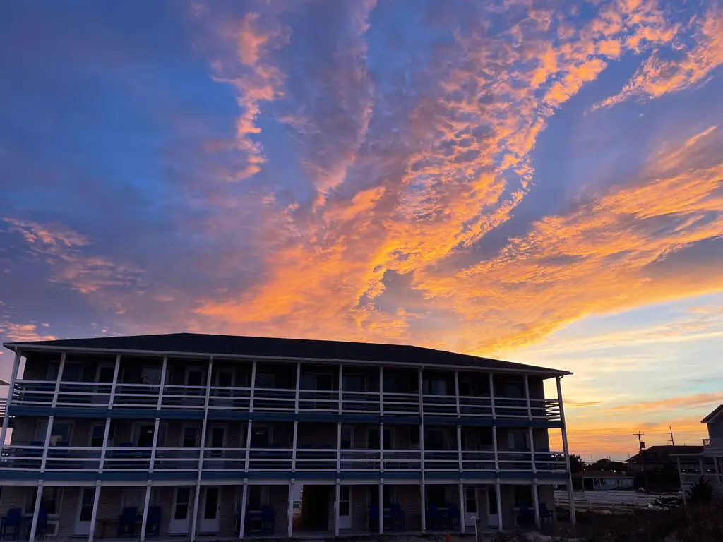 A three-storey building with balconies under a dramatic sunset sky with orange and pink clouds