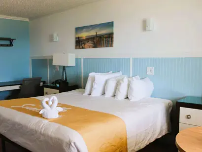 King bed beside a window in a guest room at Blue Heron Motel